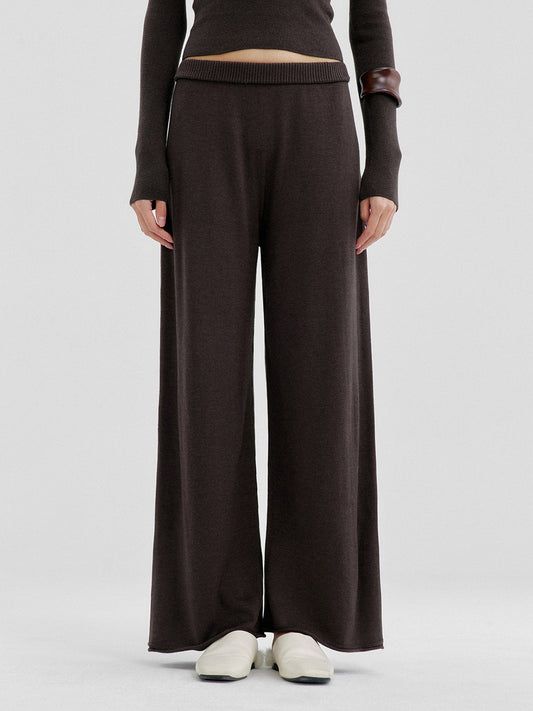 Woman wearing Arkin Studio relaxed drape knit pants in dark brown and matching top, hands down at her sides, wearing a pair of white shoes, standing facing the camera, on a white background