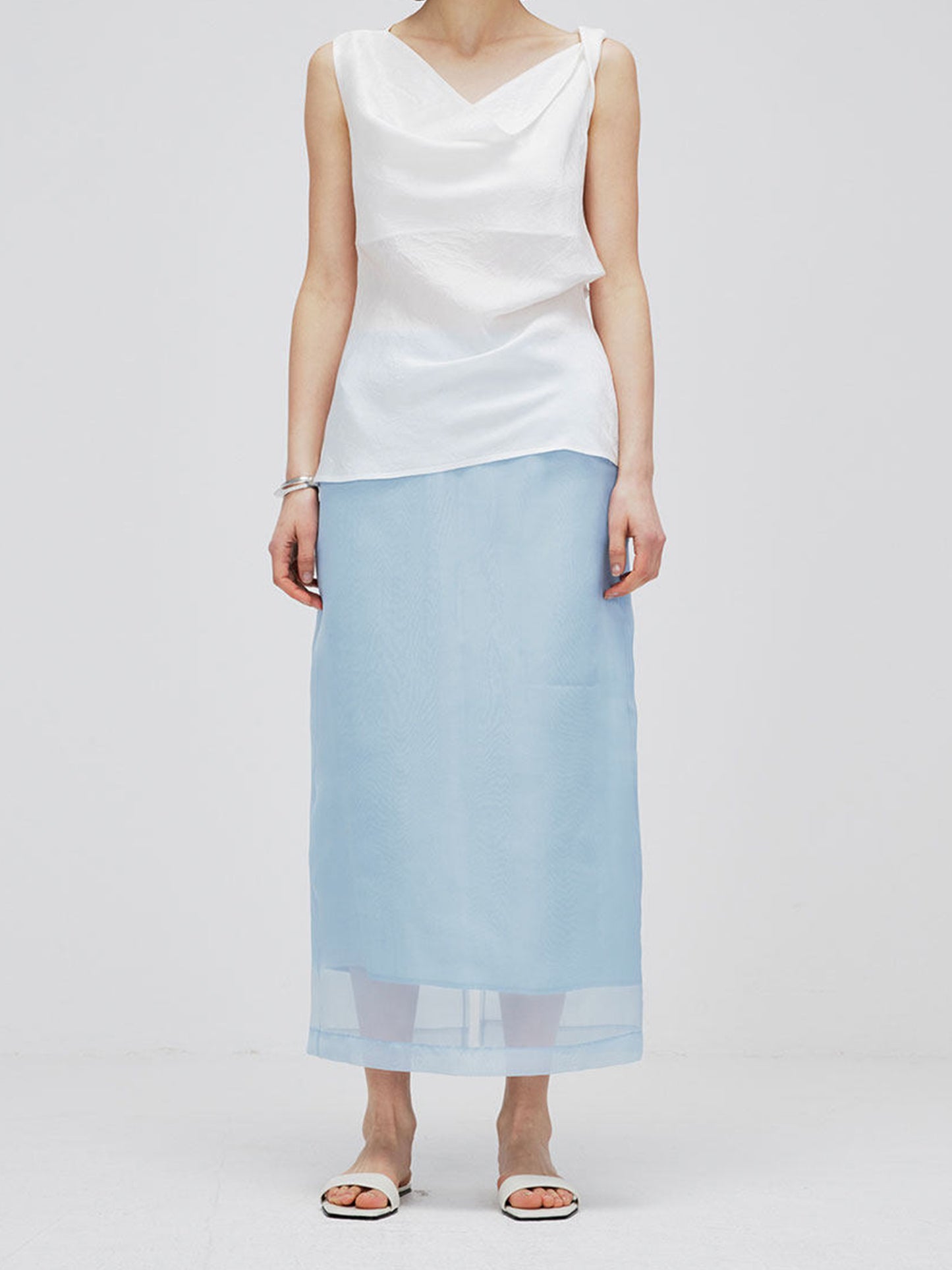 Woman wearing Arkin Studio high-waist mesh two-layer midi skirt in light blue, standing facing camera, on white background