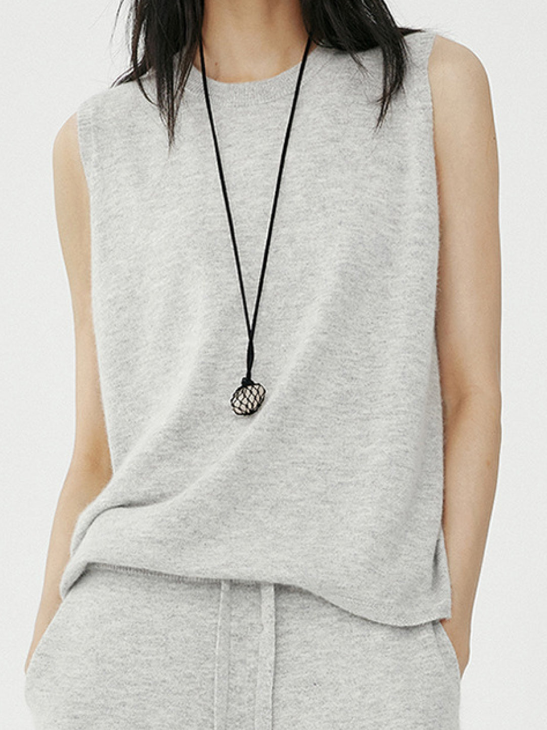 Lookbook: Women wearing Arkin Studio knit sleeveless top with crewneck in gray and gray knit pants with a long black necklace, standing and facing the camera, on a white background - shop the lookbook