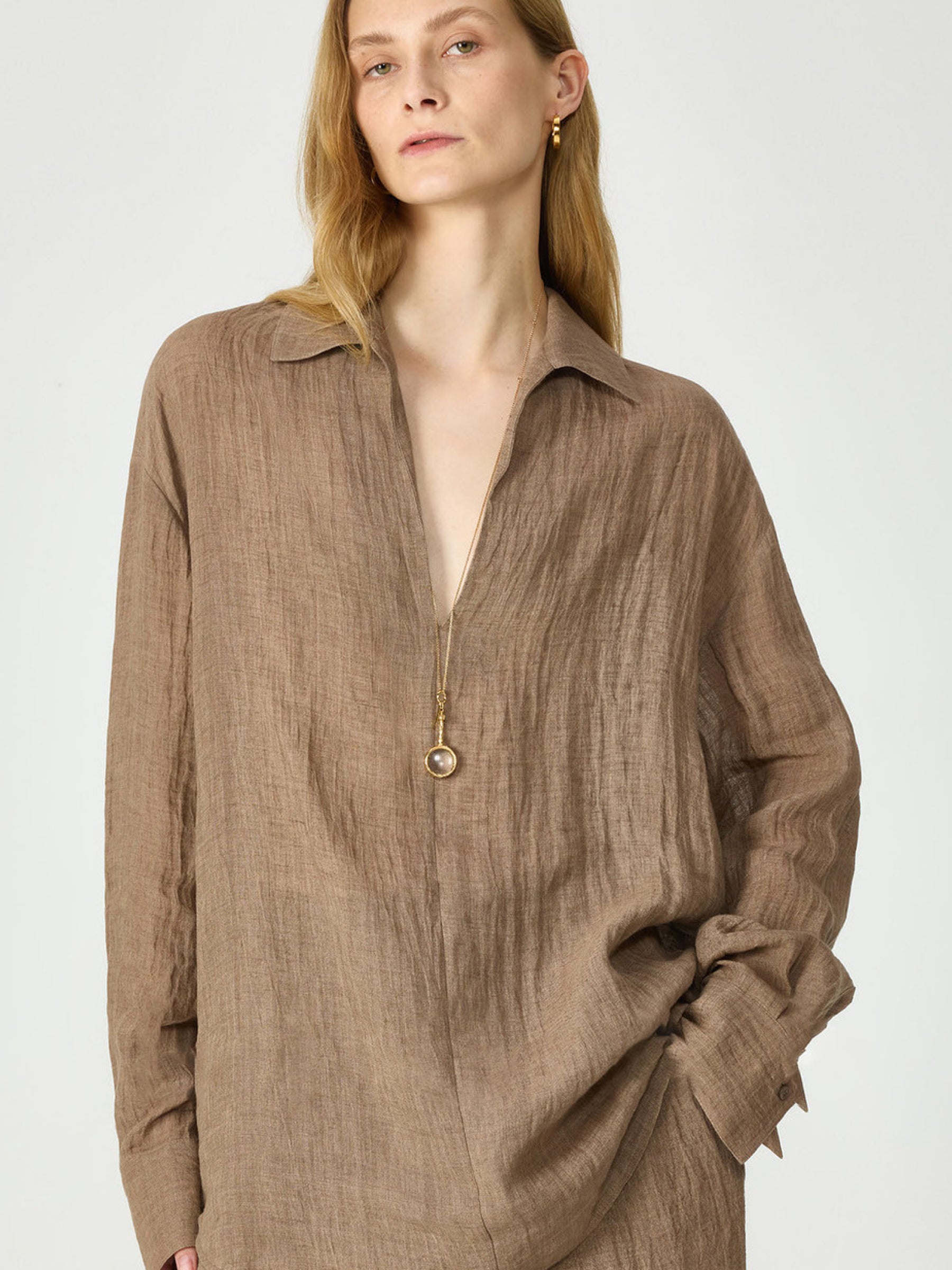 Lookbook: Woman wearing Arkin Studio relaxed crinkled linen shirt in brown and matching trousers in brown, standing and facing the camera, on a white background - shop the lookbook