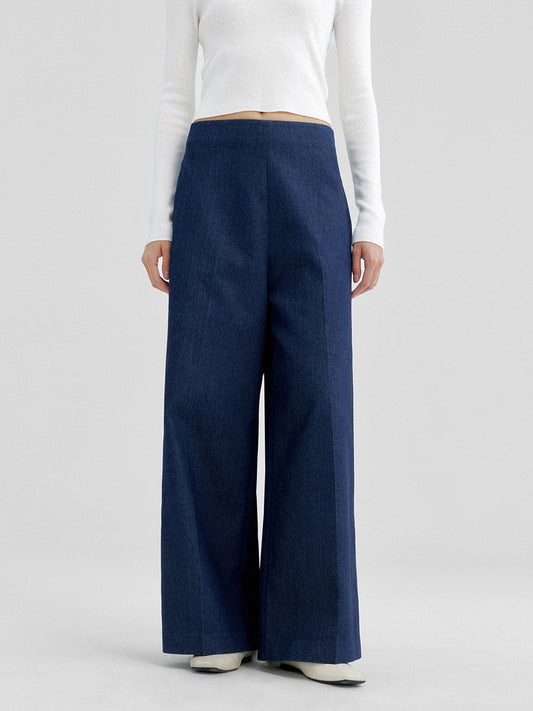 Woman wearing Arkin Studio no waistband wide leg jeans in navy and white a long sleeve top, with hands down at her sides, standing facing the camera, on a white background