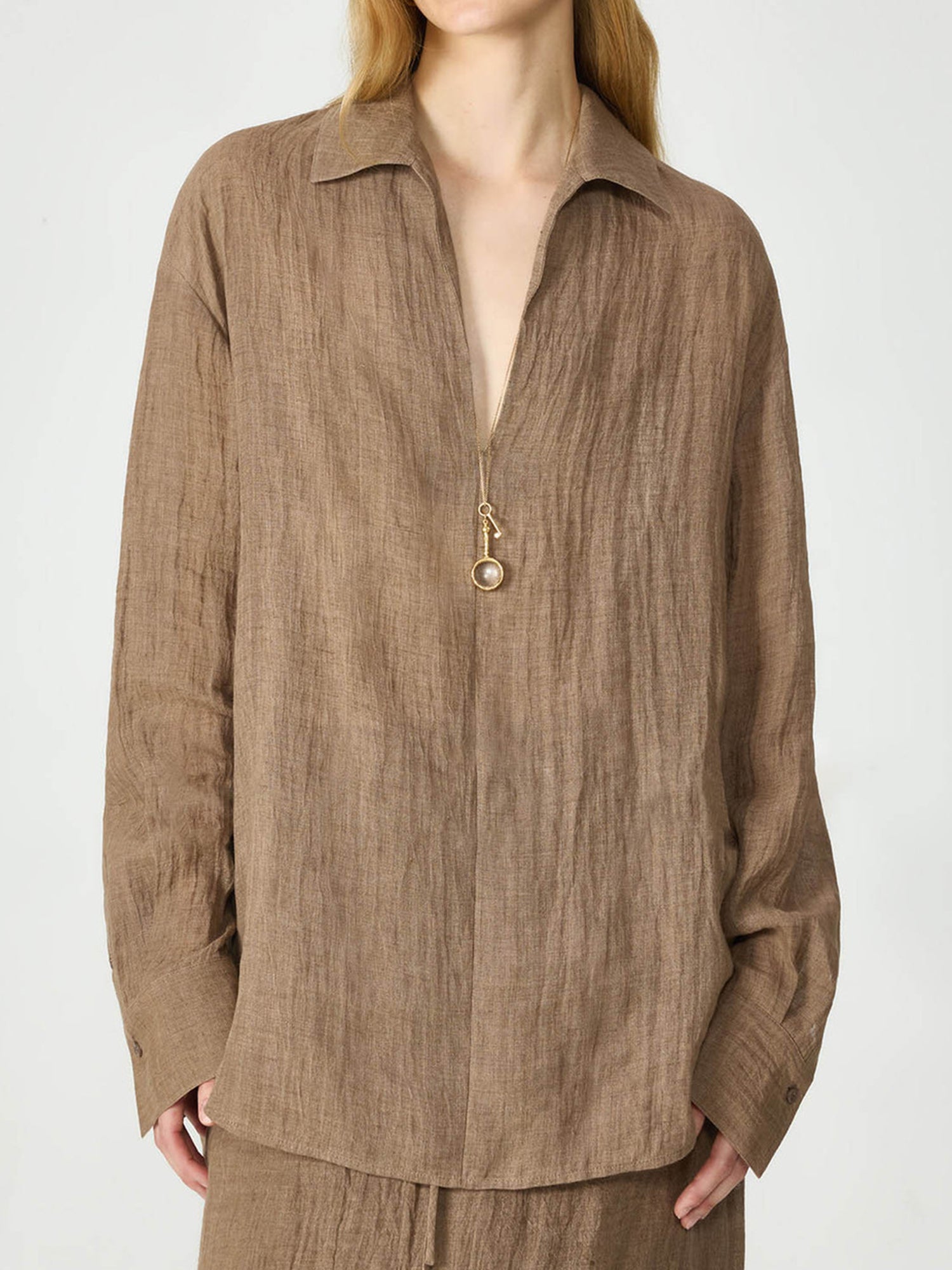 Woman wearing Arkin Studio relaxed crinkled linen shirt  in coffee and matching skirt, standing facing the camera, on a white background