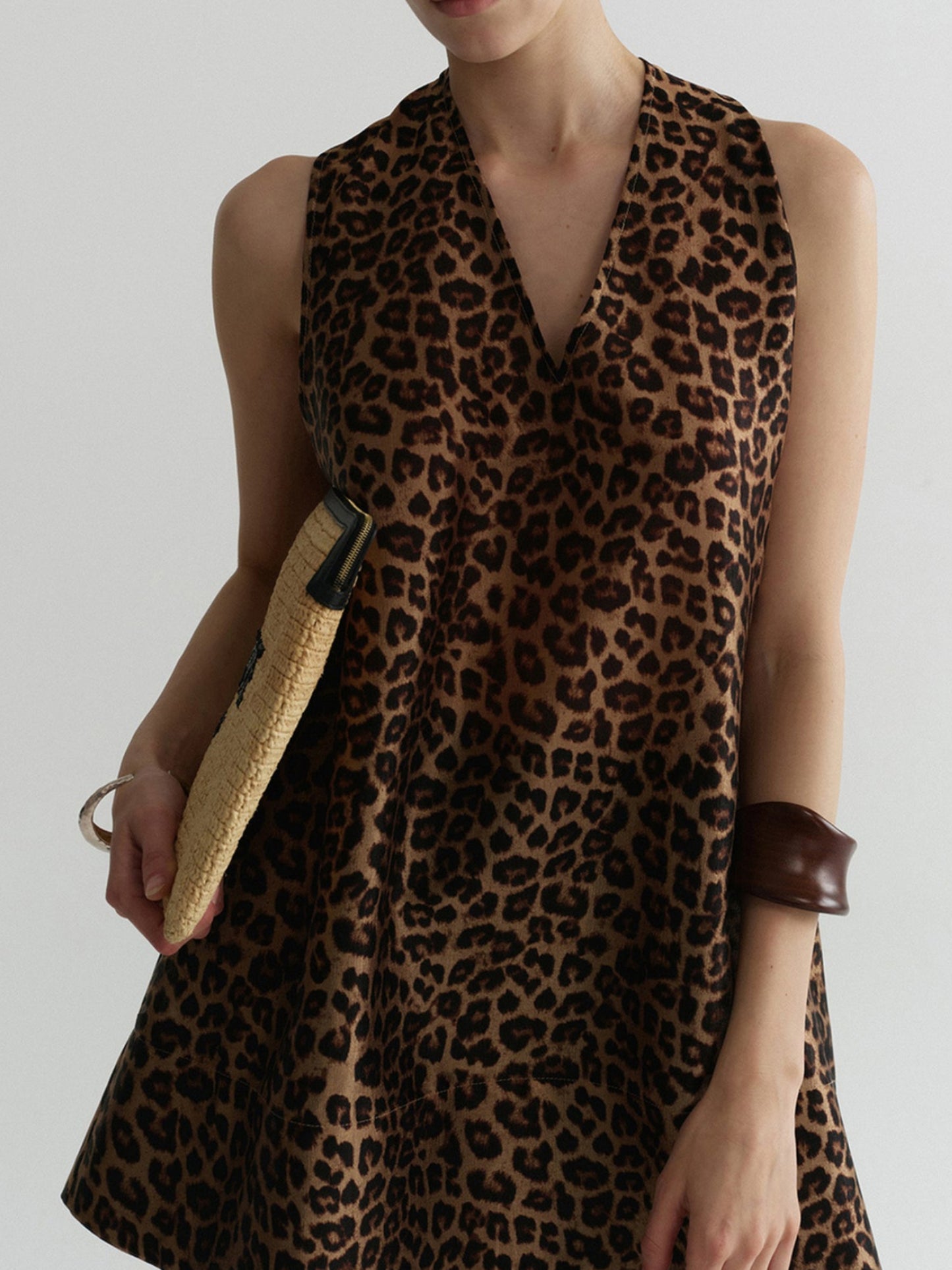 Woman wearing Arkin Studio wild leopard halter top with leopard pattern, standing facing the camera, on a white background